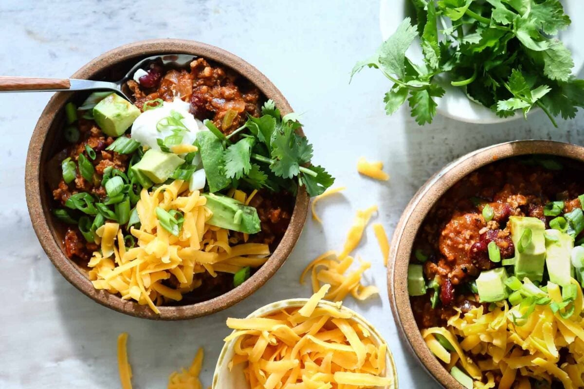 Two bowls of turkey chili with toppings.