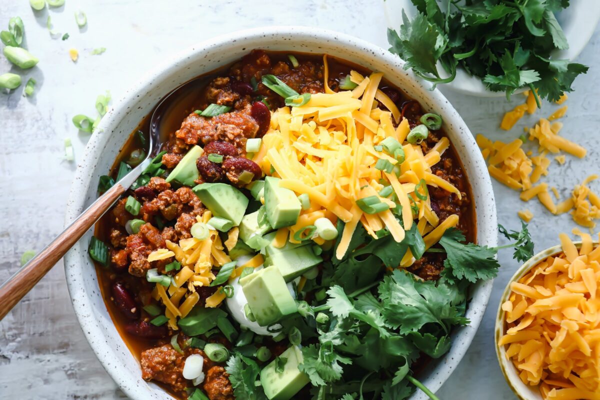 A bowl of turkey chili with toppings.