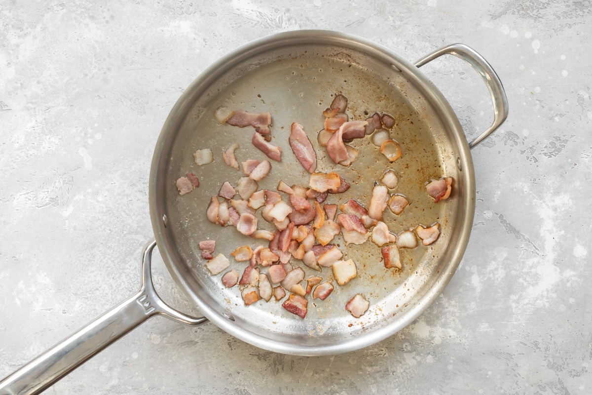 A skillet with pieces of cooked bacon inside.