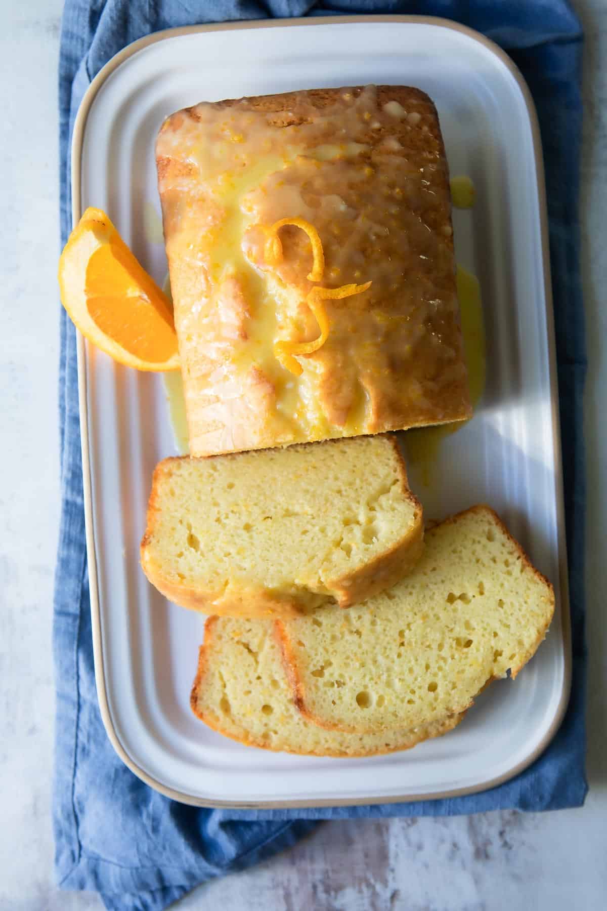 A fully baked orange loaf cake with slices cut off.
