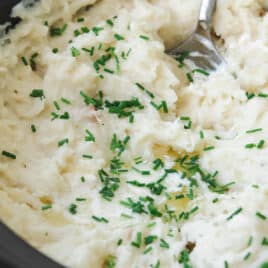 Slow cooker mashed potatoes with chives on top.