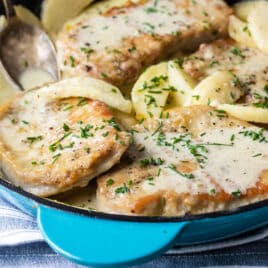 Pork Cutlets with apples in a teal skillet.