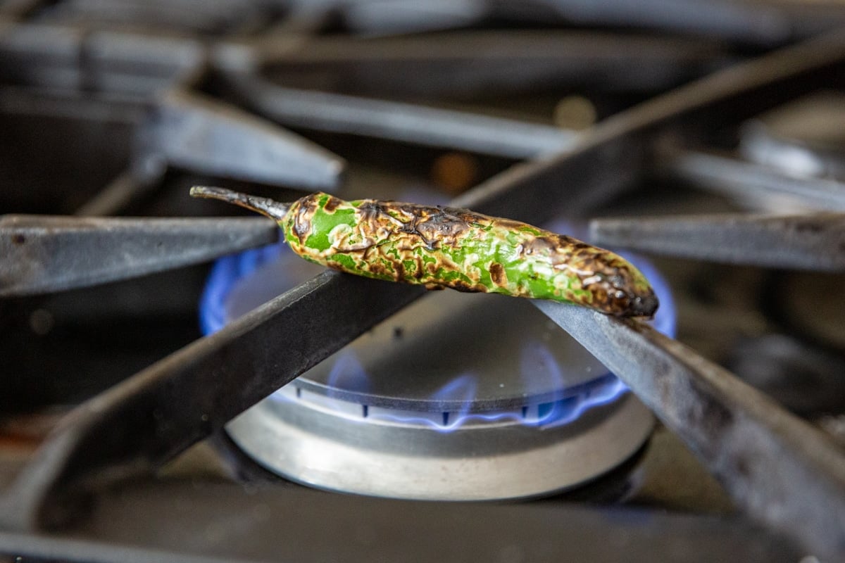 A serrano chile roasting over a gas flame.