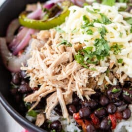 A burrito bowl filled with Chipotle copycat Carnitas, white rice, black beans, salsa, and fajita veggies.