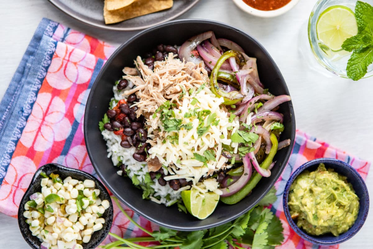 A burrito bowl filled with Chipotle copycat Carnitas, white rice, black beans, salsa, and fajita veggies.