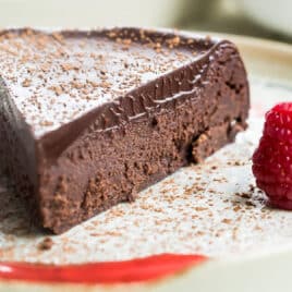 Flourless chocolate cake slice on a white plate.