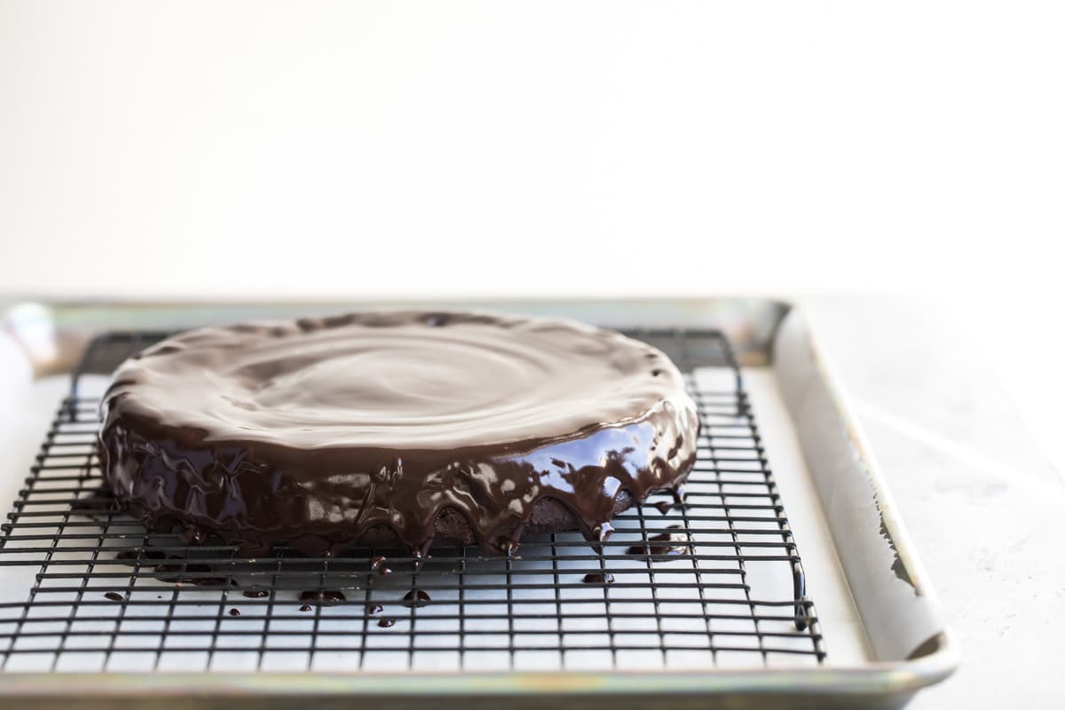 Flourless chocolate cake with chocolate glaze on a cooling rack.