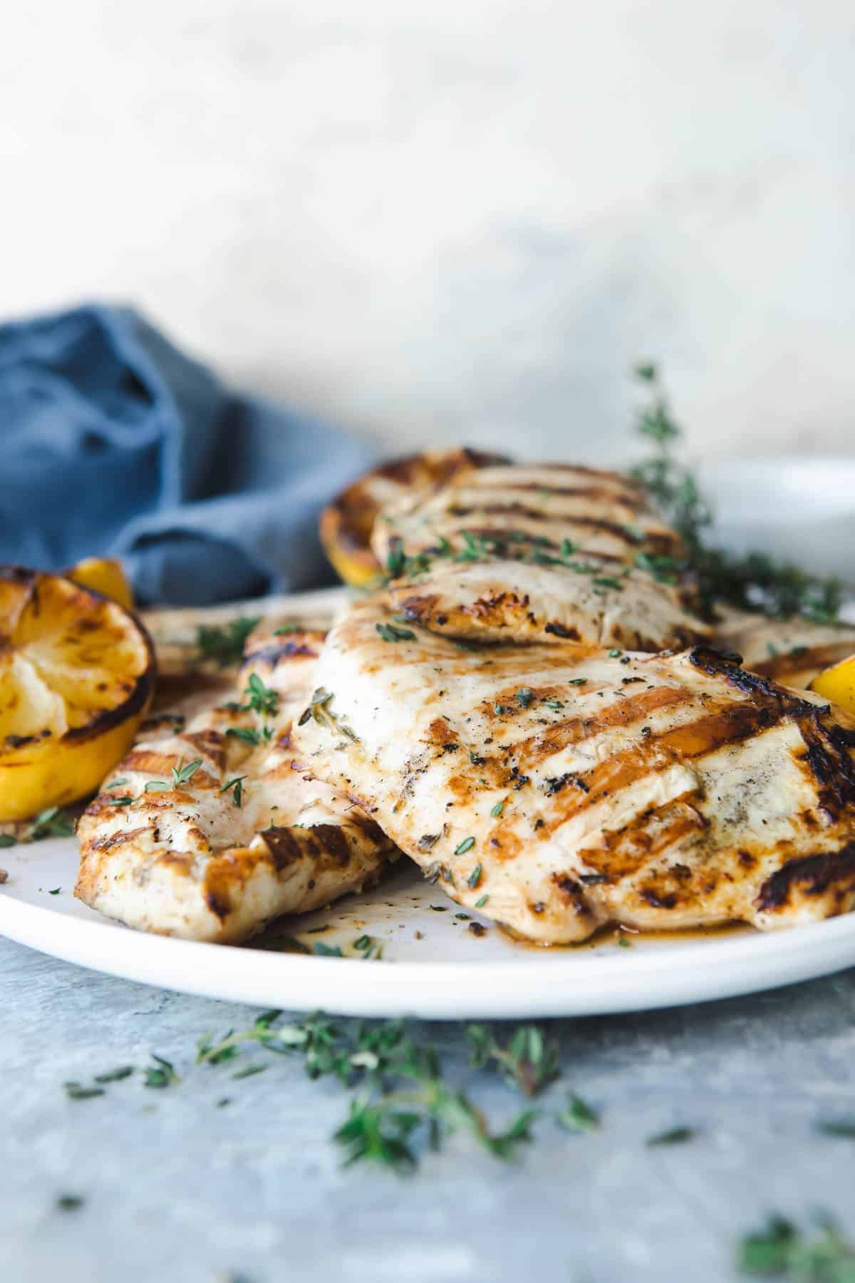 A platter full of grilled lemon chicken breasts.