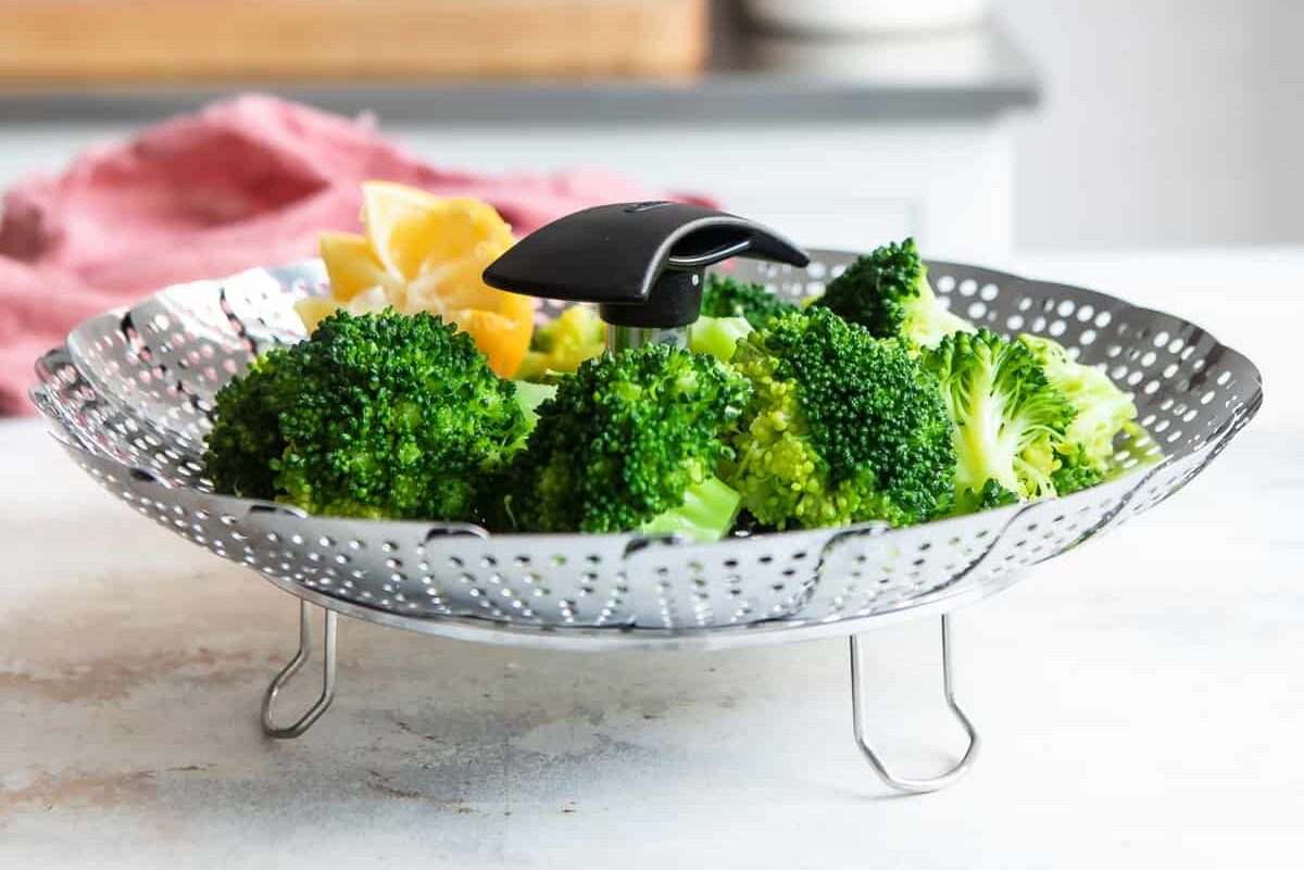 A steamer basket with broccoli in it.