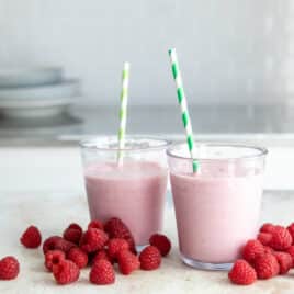 Two raspberry smoothies on a countertop.