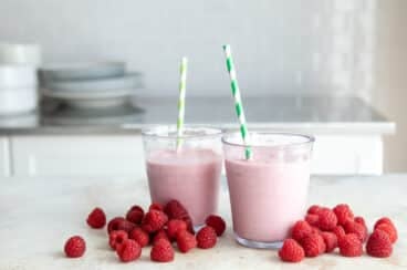 Two raspberry smoothies on a countertop.