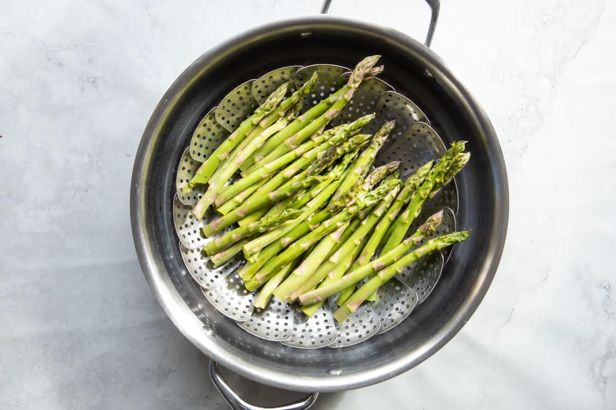 Raw asparagus in a steamer basket.
