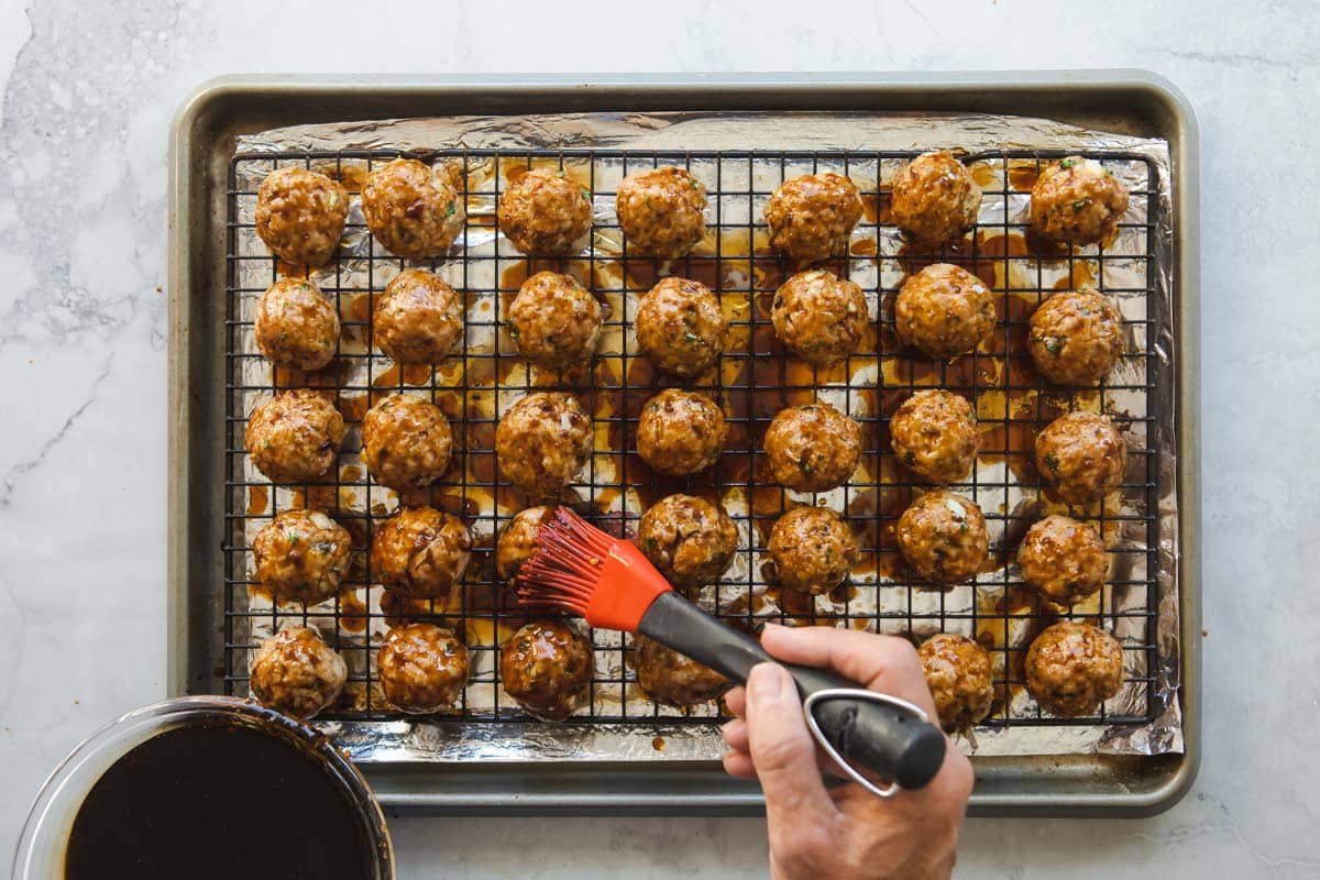 A baking rack filled with glazed teriyaki meatballs.