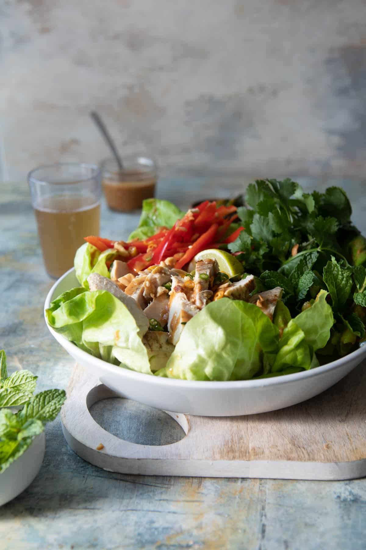 A Thai chicken salad on a plate with a small jar of dressing next to it.