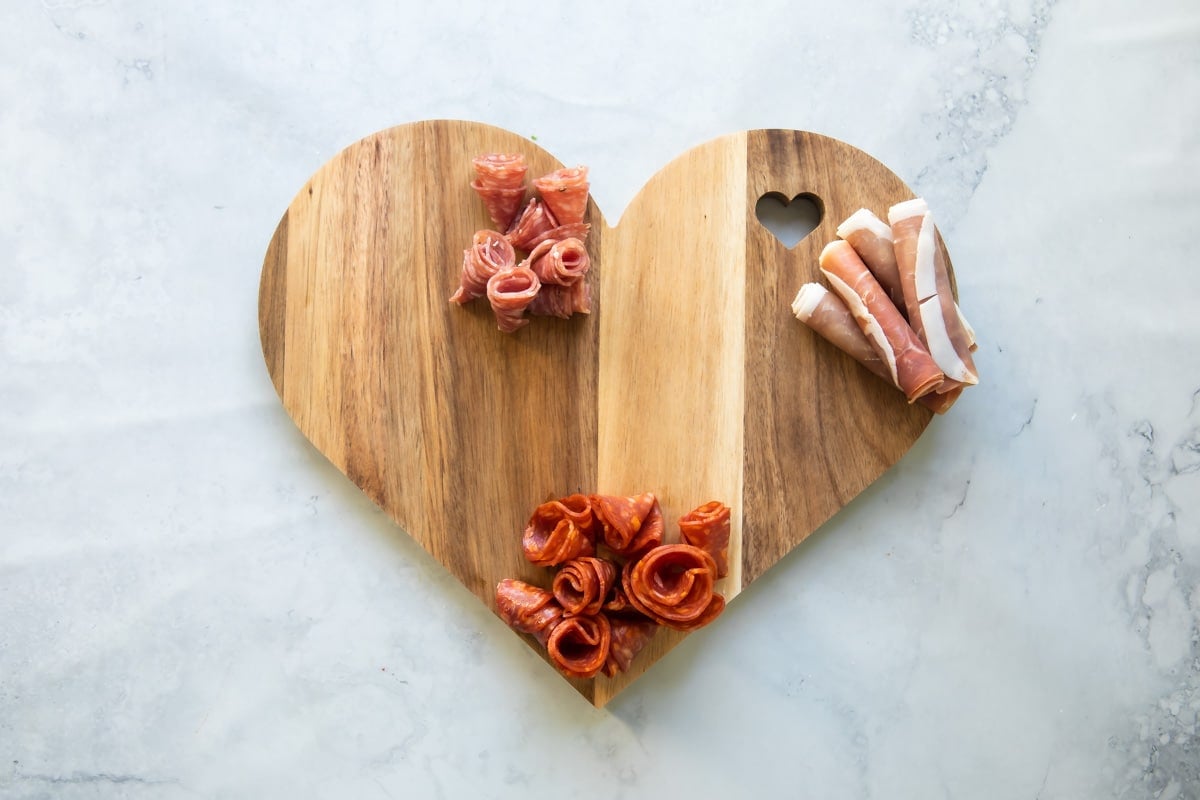 Adding meat to a Valentine's Day charcuterie board.