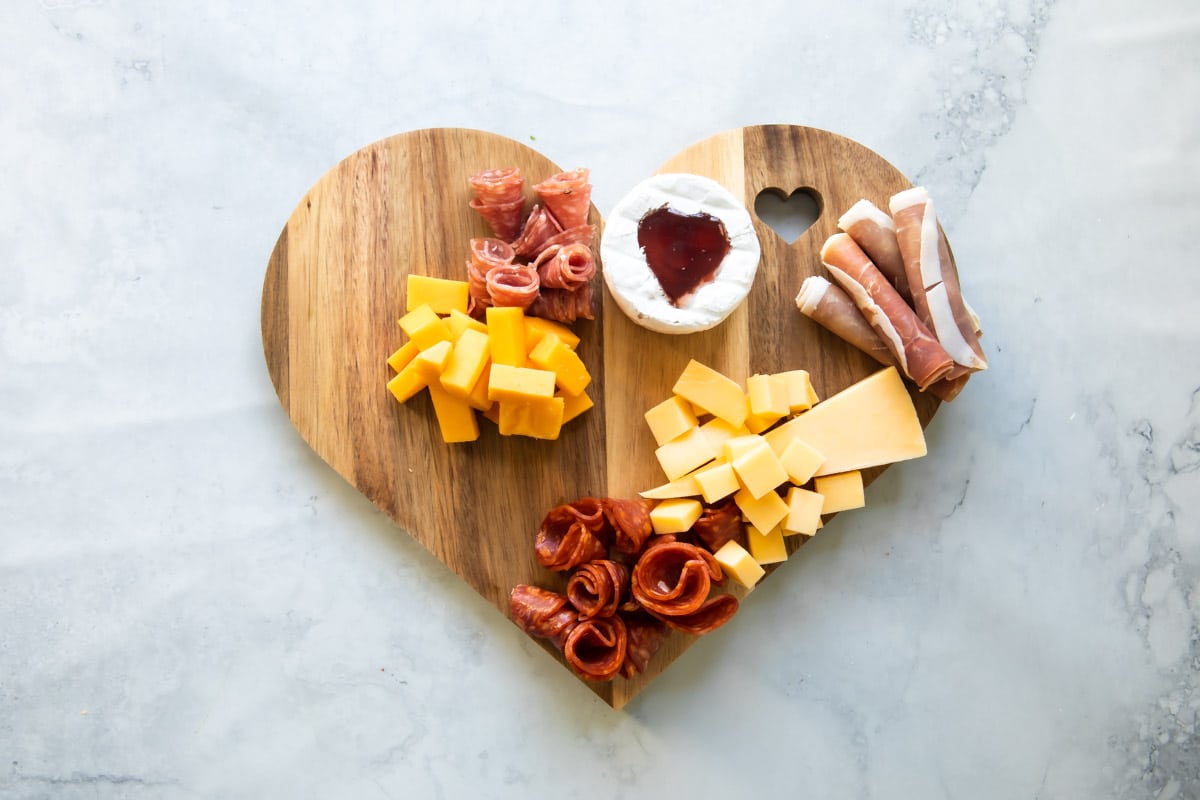 Meat and cheese on a valentine's day charcuterie board.