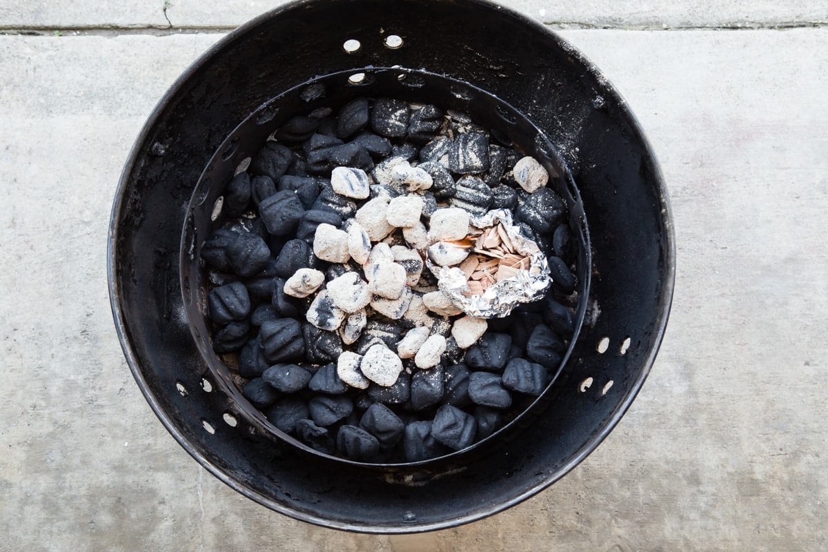Charcoal with a packet of hardwood in a smoker.