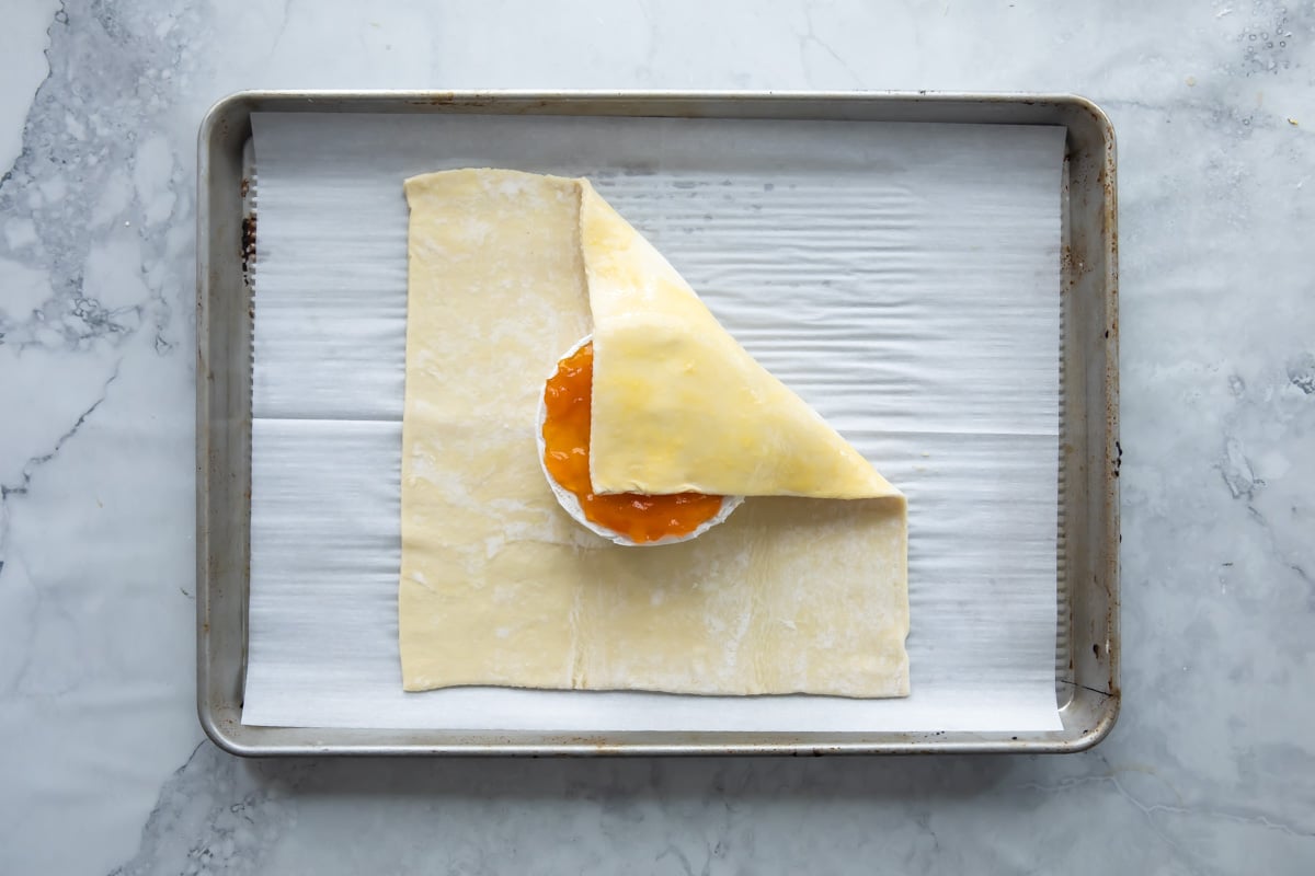 Wrapping a wheel of brie with apricot ja on top in puff pastry.