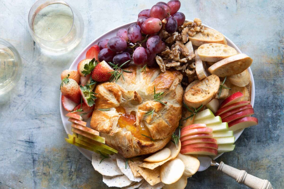Baked brie wrapped in puff pastry served with fruit and crostini.
