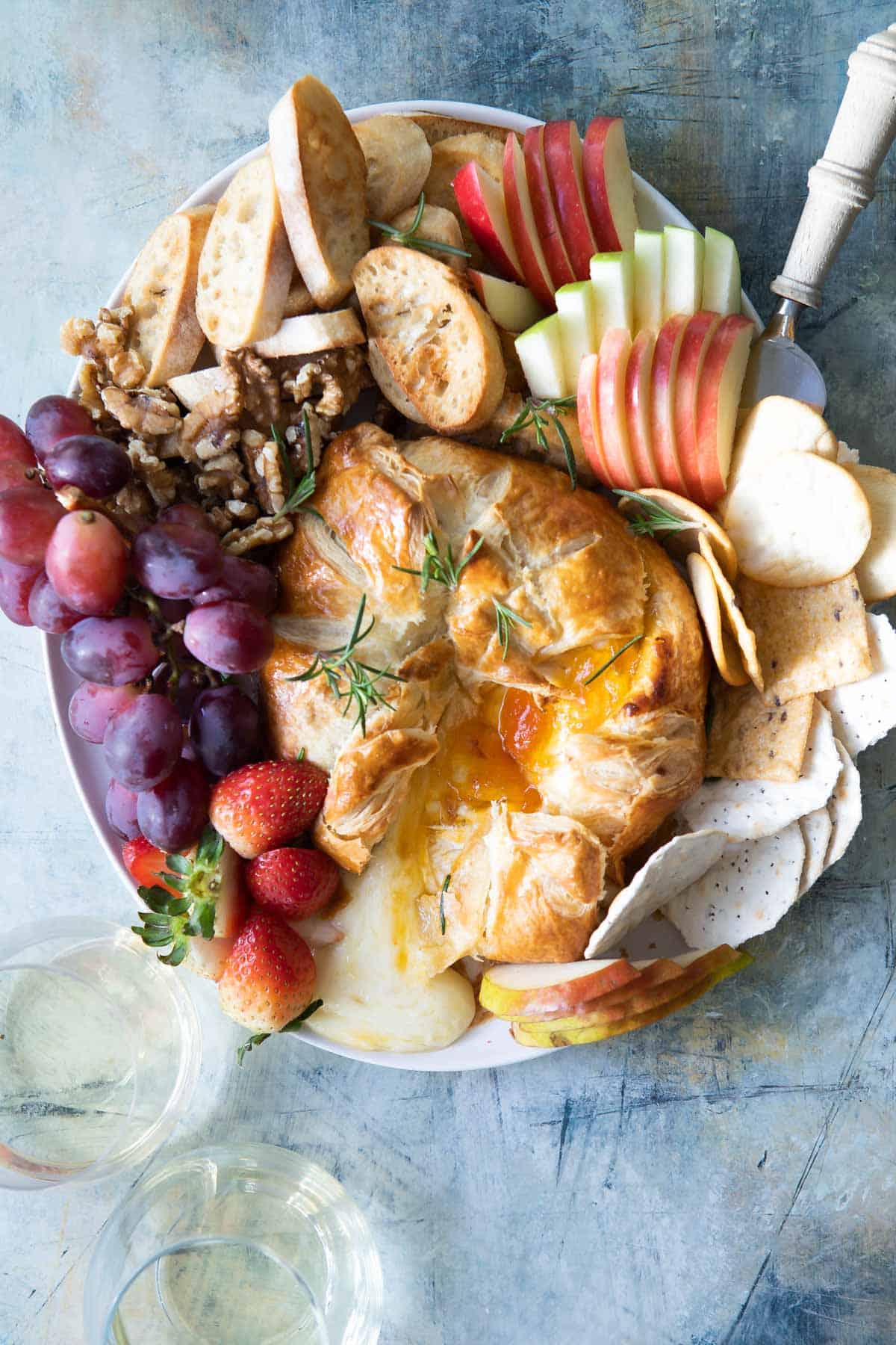 Baked brie wrapped in puff pastry served with fruit and crostini.