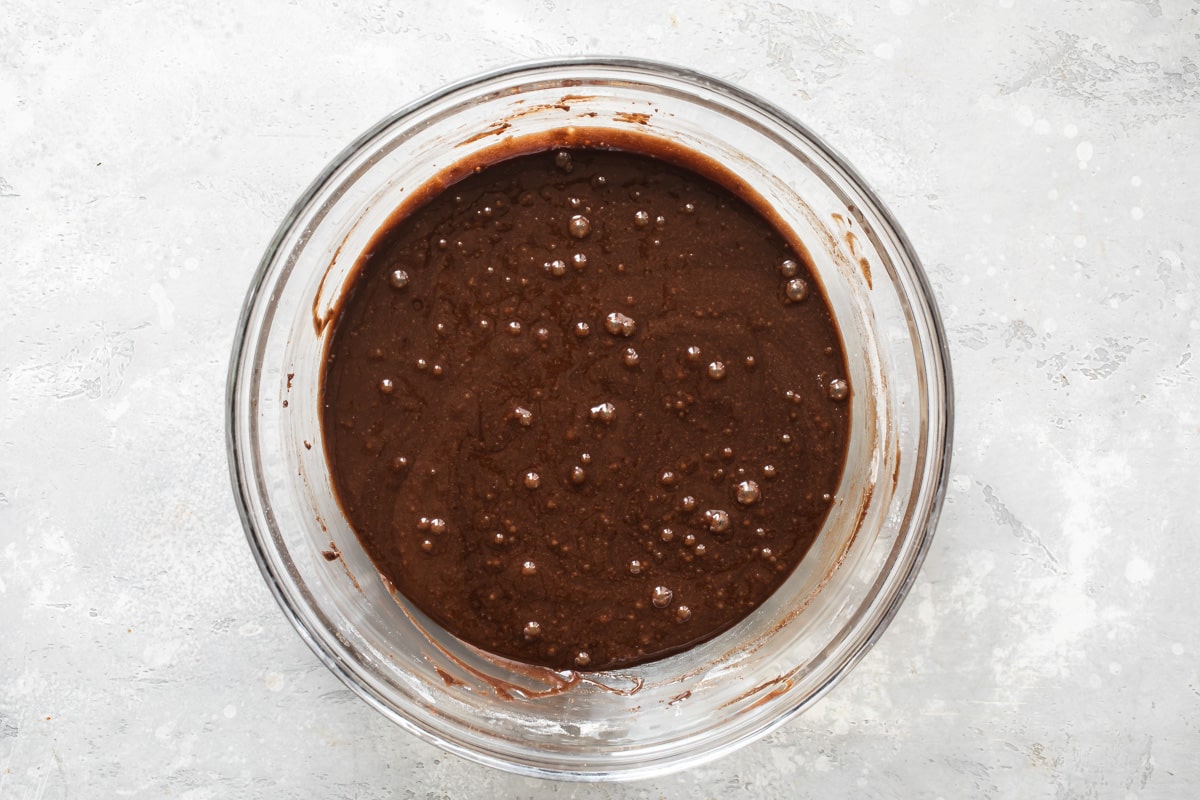 Brownie batter in a clear glass bowl.