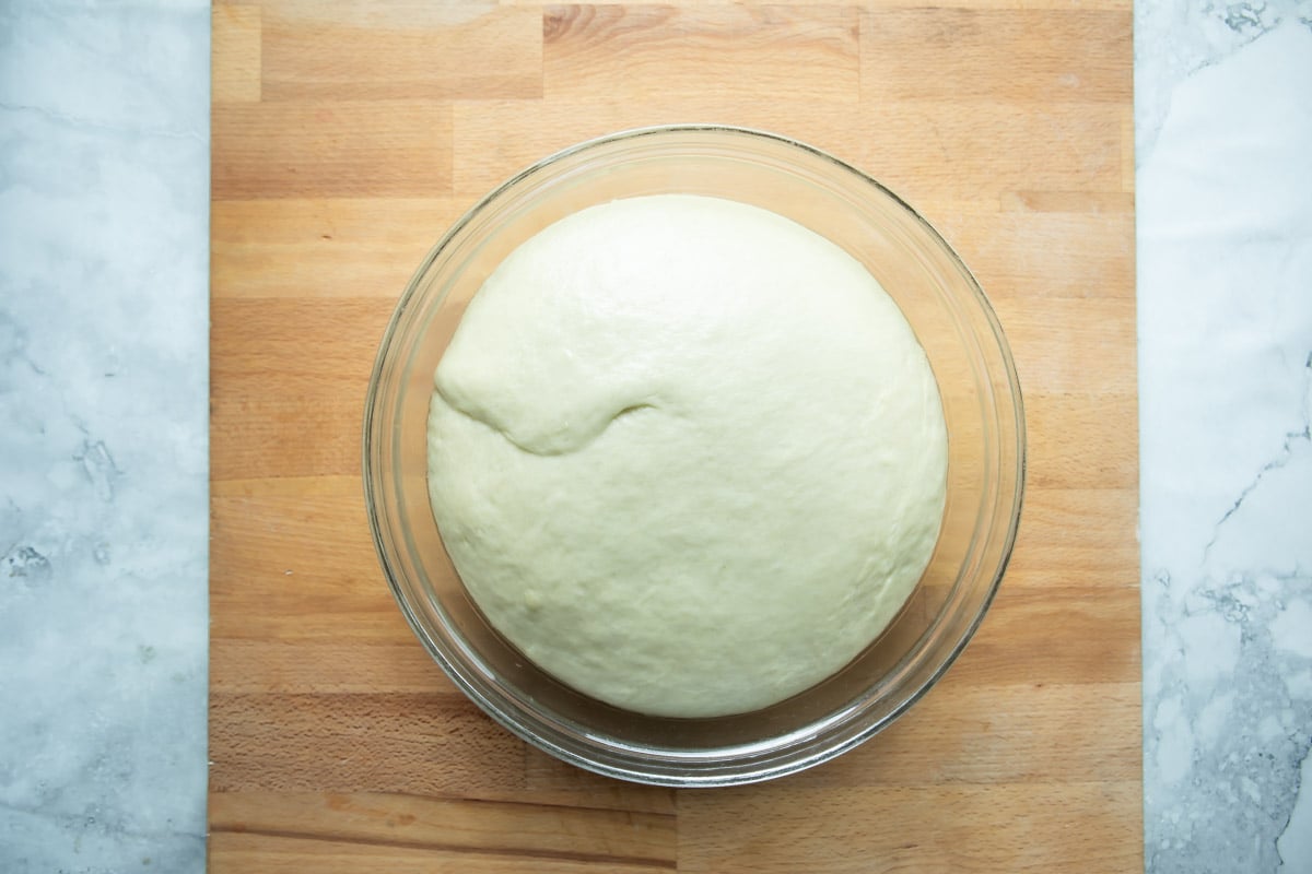 A ball of dough after rising in a glass bowl.