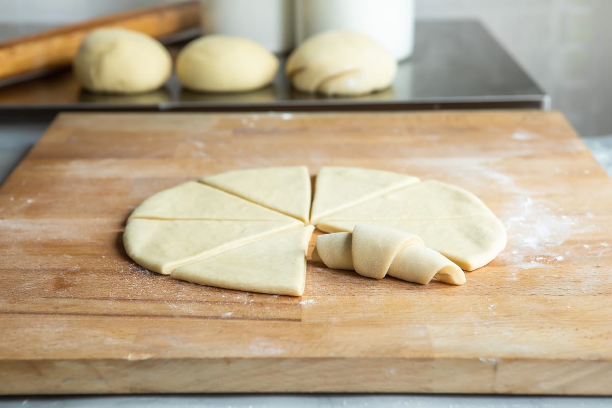 A circle of dough cut into 8 pieces, 1 wedge rolled into a crescent shape.