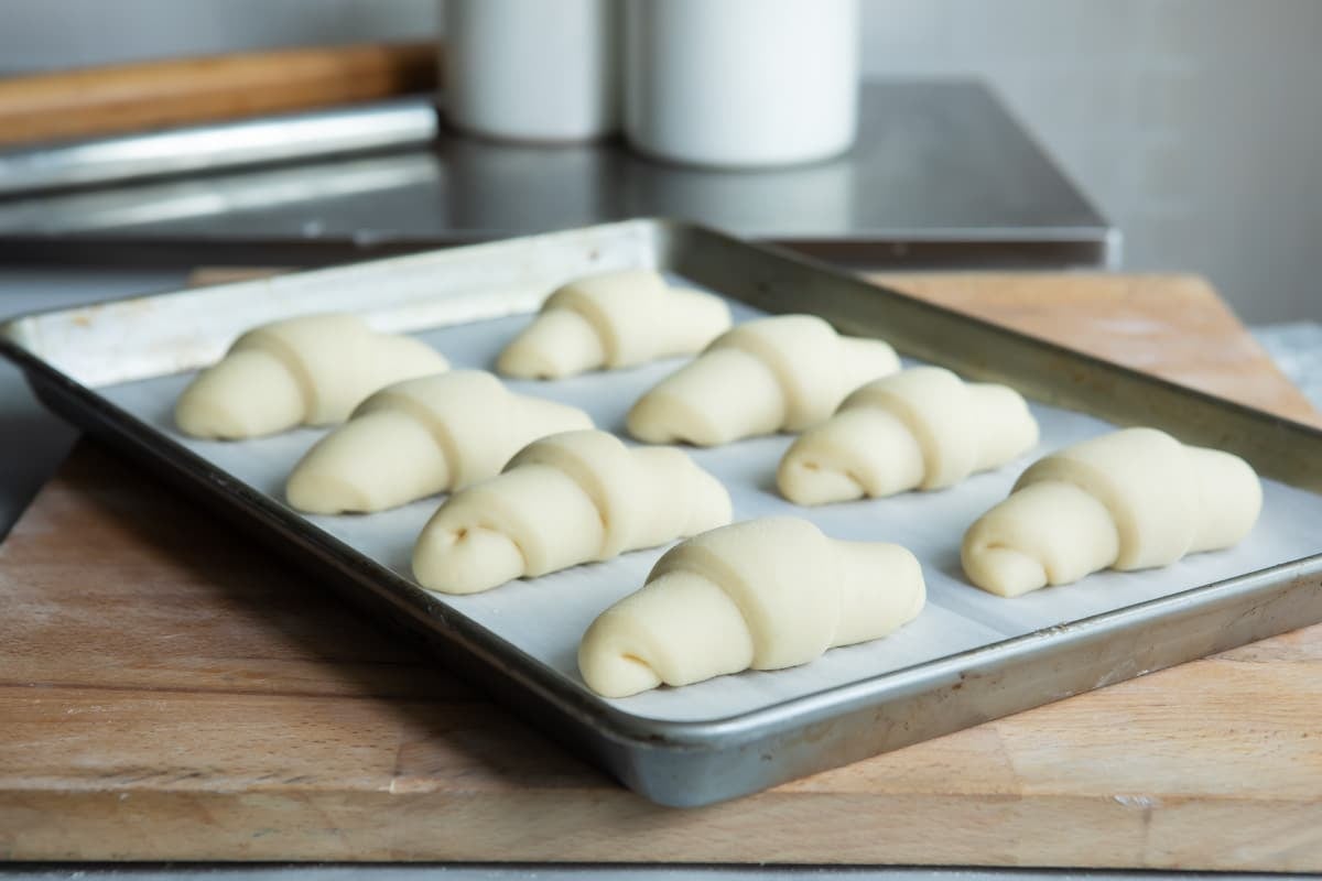 8 risen crescent rolls on a baking sheet before baking.