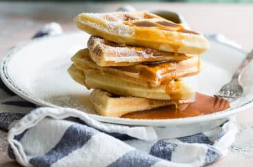 A stack of homemade waffles with syrup.