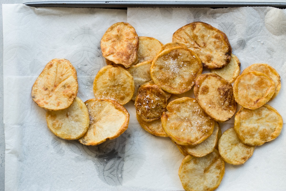 Fried potato slices draining on paper towels.