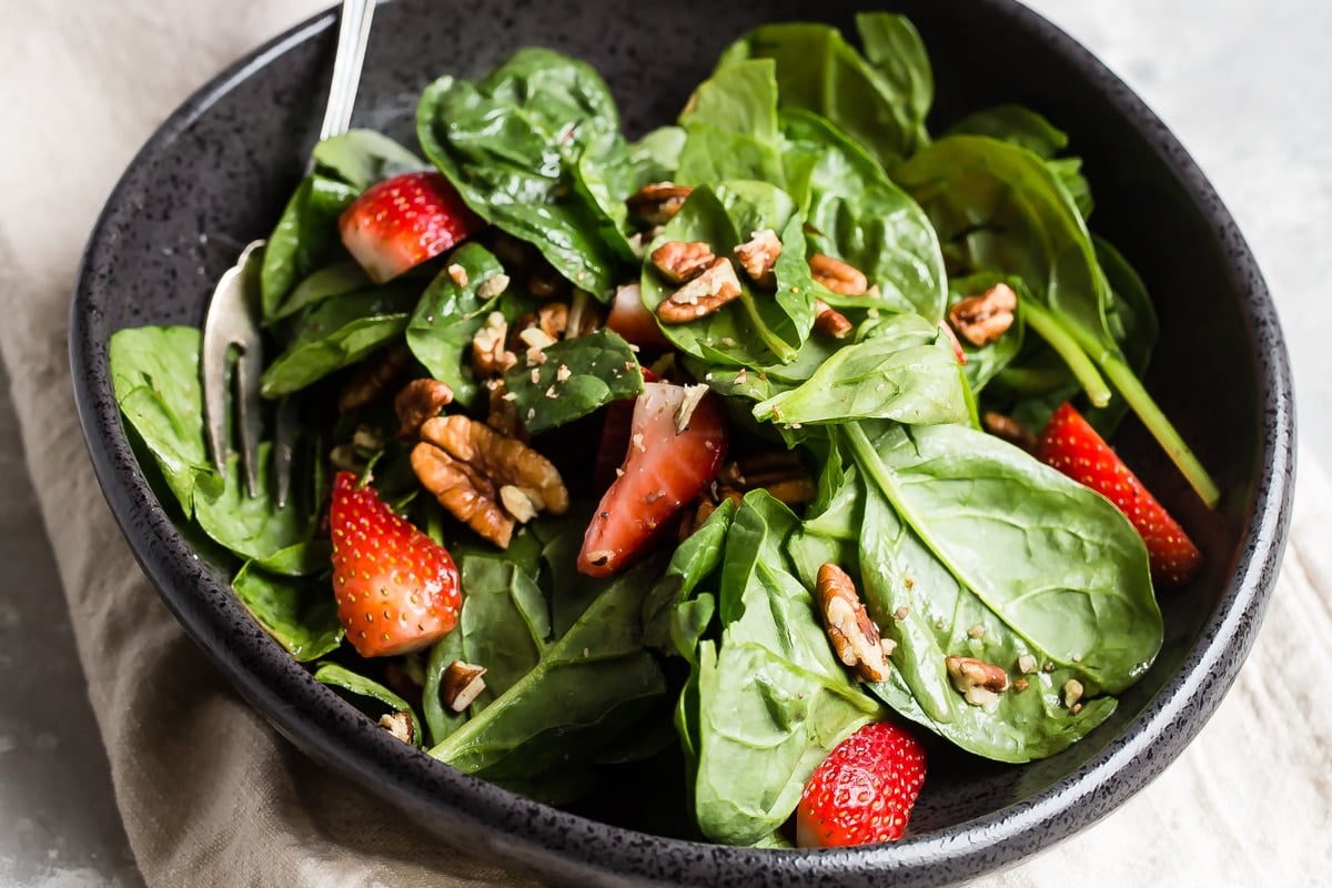 Strawberry spinach salad in a black bowl.