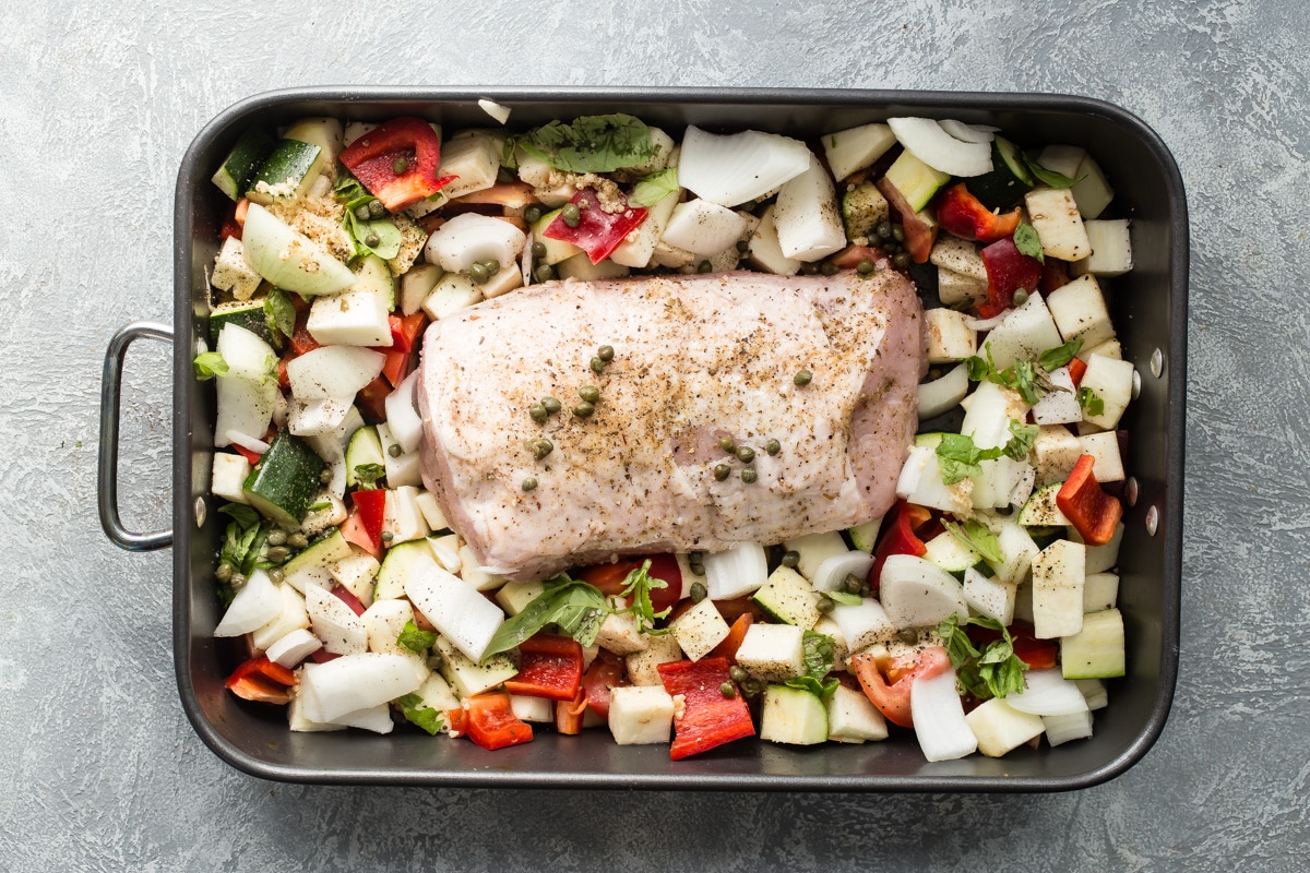 Pork loin with ratatouille in a black baking pan.