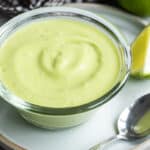 A small bowl of avocado sauce on a plate.