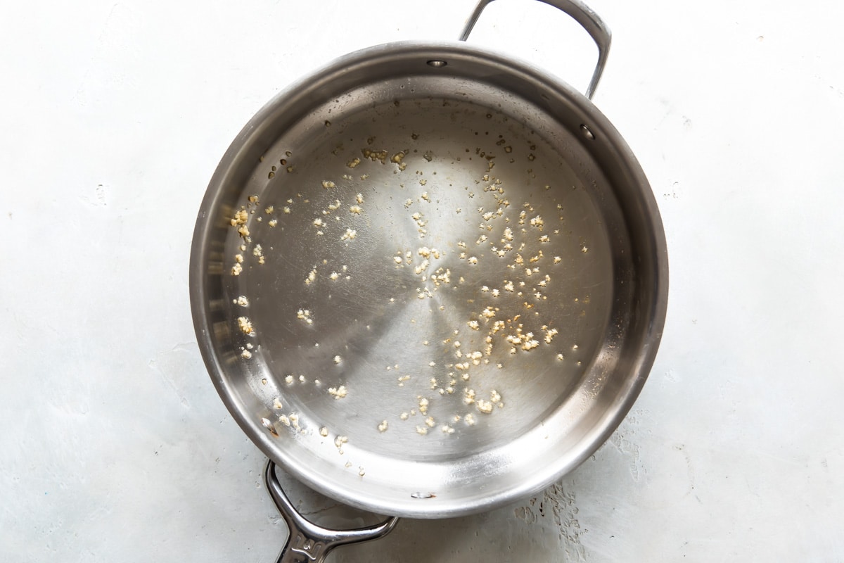 Minced garlic sizzling in olive oil in a skillet.