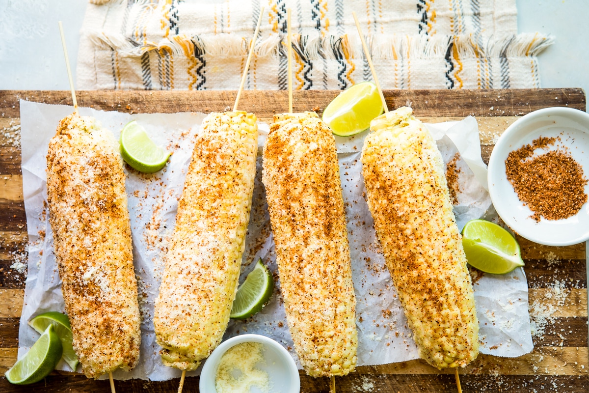 Ears of Mexican Street Corn on a board with lime slices.