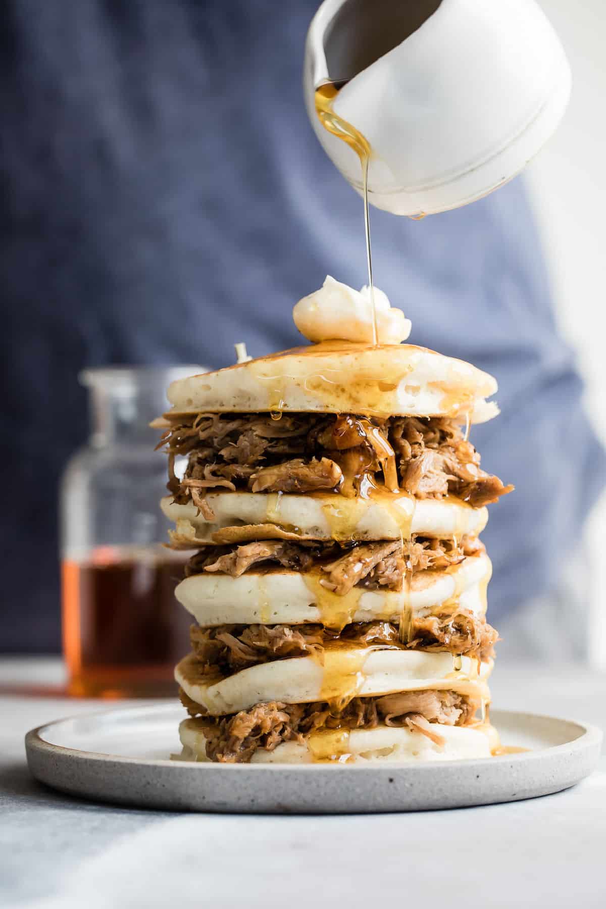 A stack of pulled pork pancakes with butter and whisky maple syrup on top.