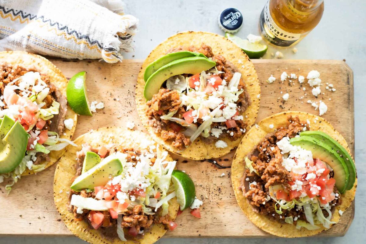Tostadas on a board next to a bottle of beer.