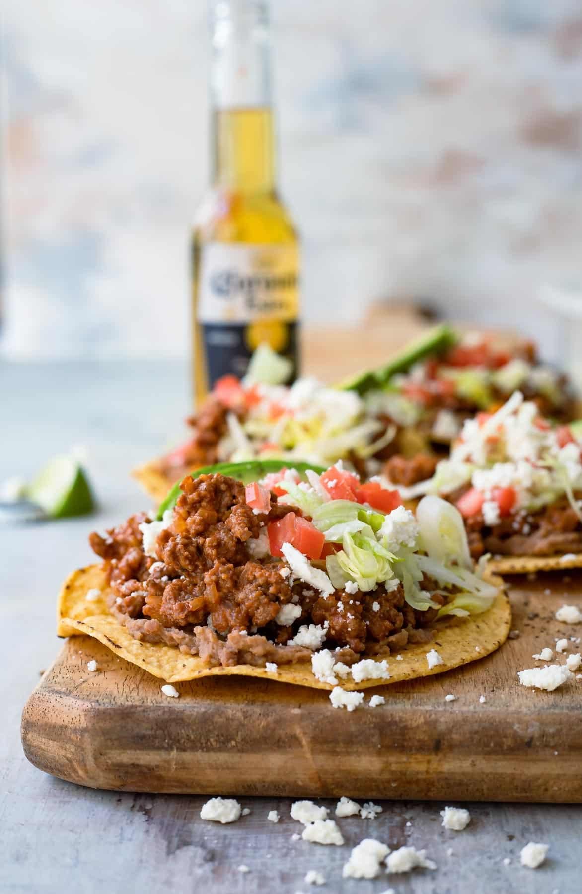 Tostadas on a board next to a bottle of beer.