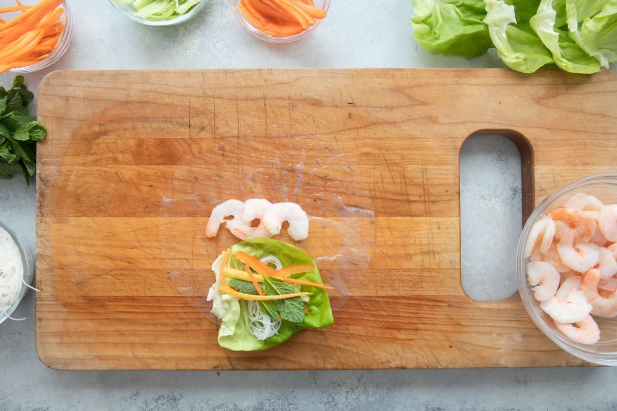 Assembling a Vietnamese spring roll with shrimp and veggies.