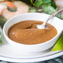 Vietnamese Peanut Sauce in a white bowl with a spoon resting in it.