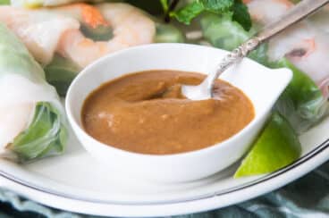 Vietnamese Peanut Sauce in a white bowl with a spoon resting in it.